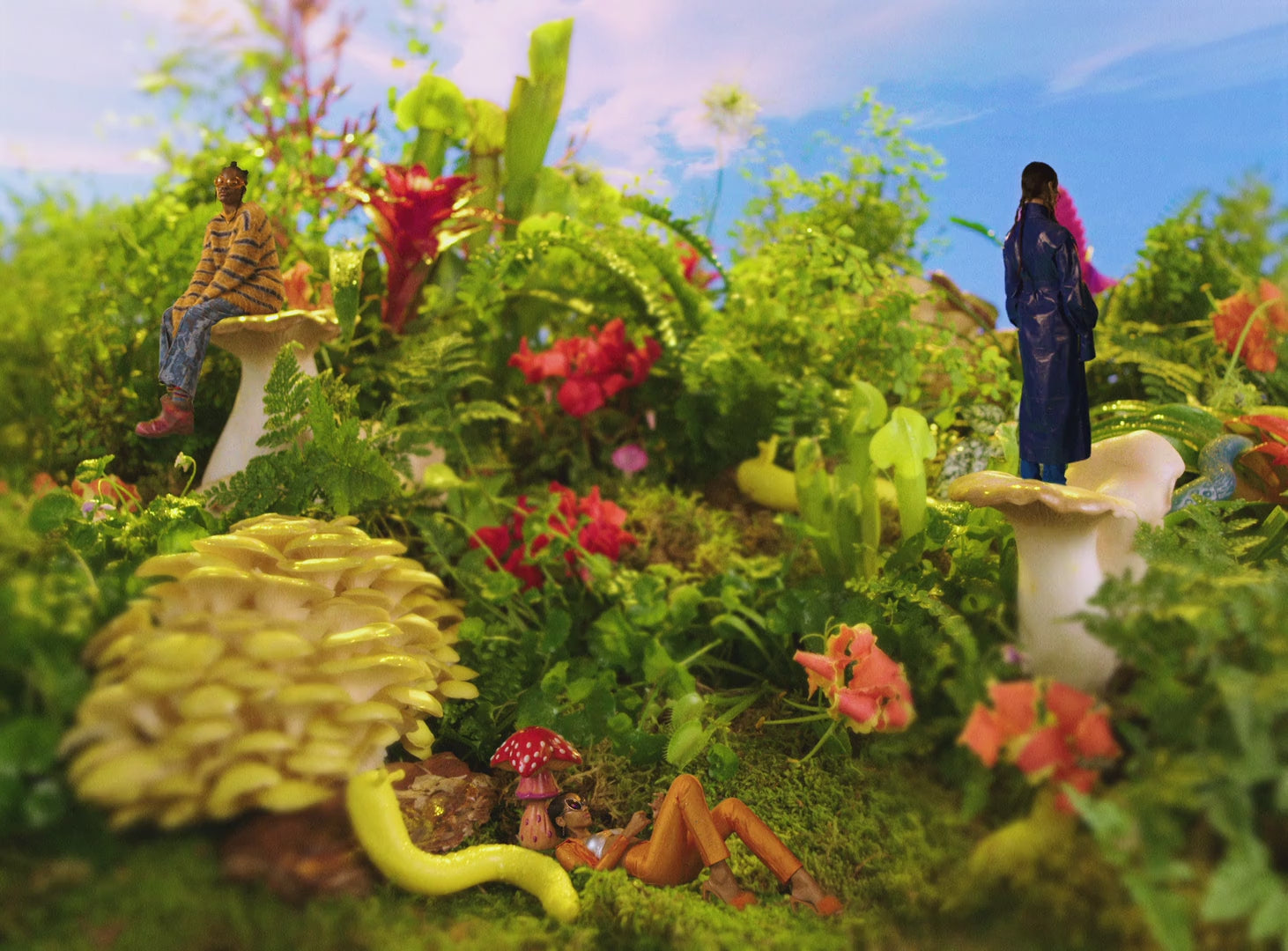 Three people lounge among mushrooms and rich vegetation as clouds pass by.